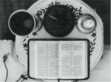 La Bibbia aperta su un tavolo, con un calice, un piatto e una candela accesa, oggetti del rituale che precedeva il channeling
