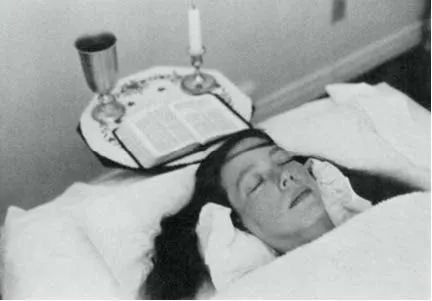 Carla Rueckert distesa con gli occhi chiusi durante una sessione di channeling, con un calice, una candela e un libro aperto accanto