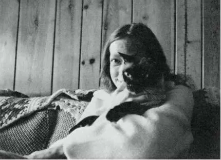 Carla Rueckert seduta su un divano con un gatto in braccio, in una foto in bianco e nero