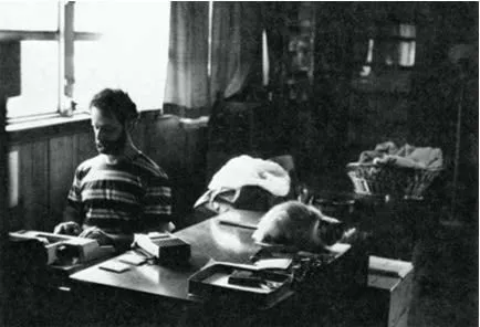 L’uomo alla macchina da scrivere trascrive una sessione, con un gatto sdraiato sul tavolo accanto a lui. Fotografia d’archivio in bianco e nero