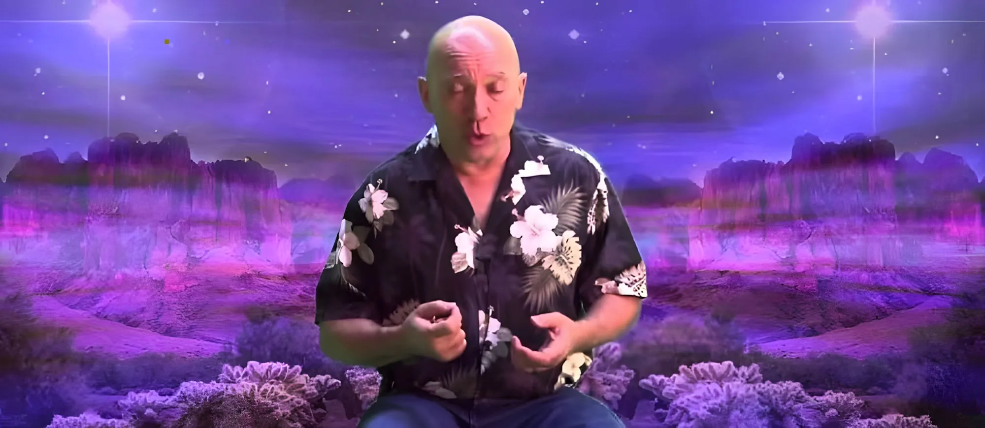 Uomo calvo in camicia a fiori che parla gesticolando, su uno sfondo viola con un paesaggio desertico e stelle