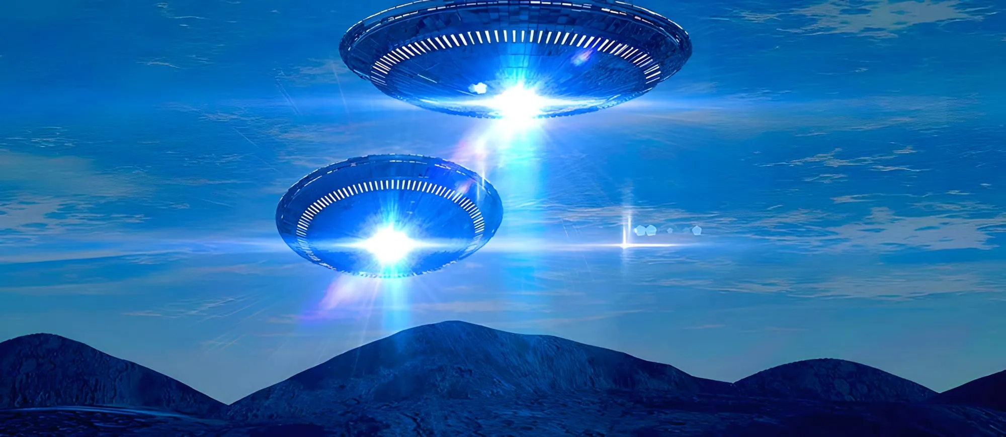 Due dischi volanti luminosi sospesi nel cielo blu sopra delle colline
