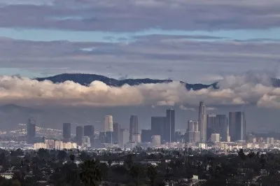 The San Gabriel Mountains are seen in the background during cloud cover over the Los Angeles skyline